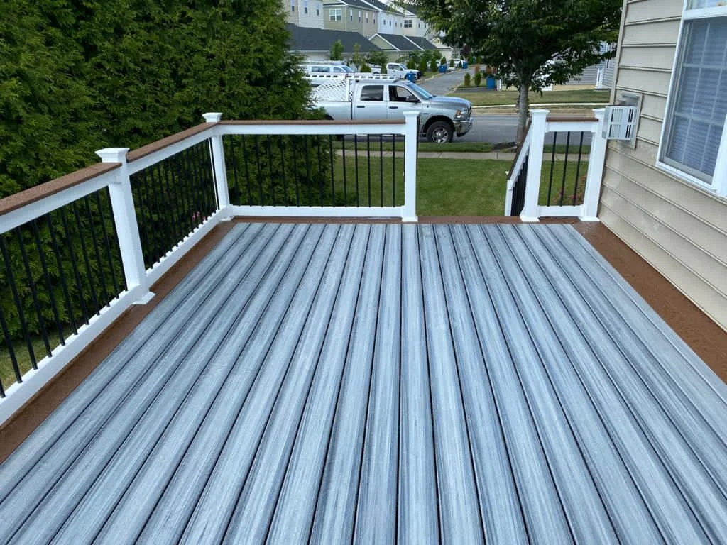 Gray deck with white railings beside a home