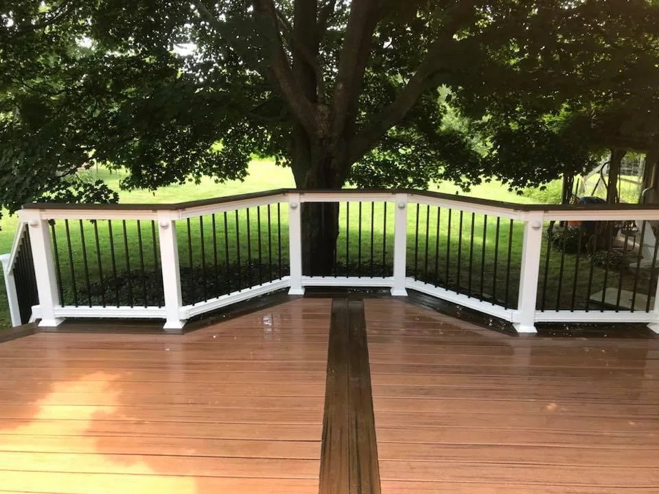 Brown deck beneath a shade tree with white railing