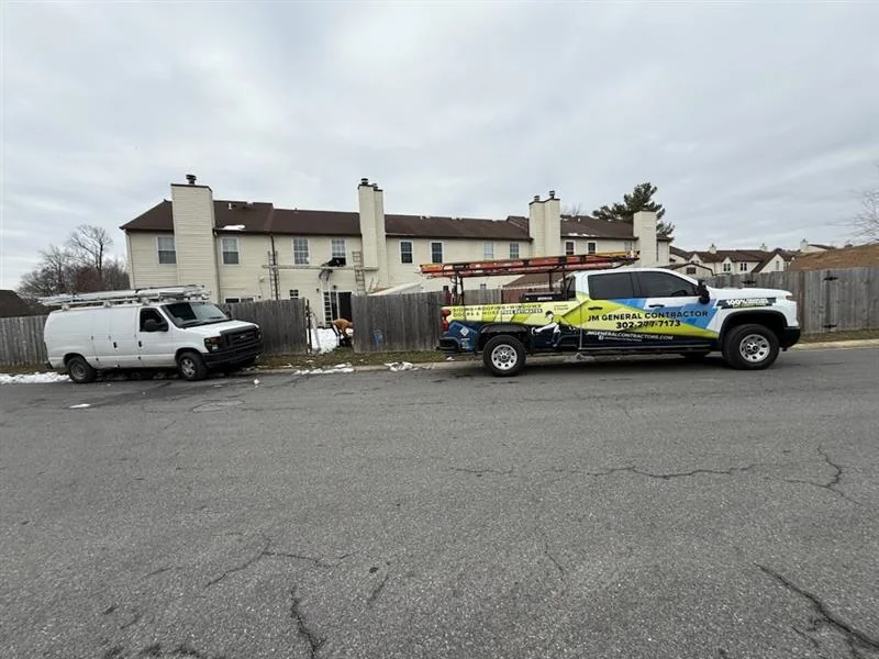 JM General Contractors trucks and trailer on a street