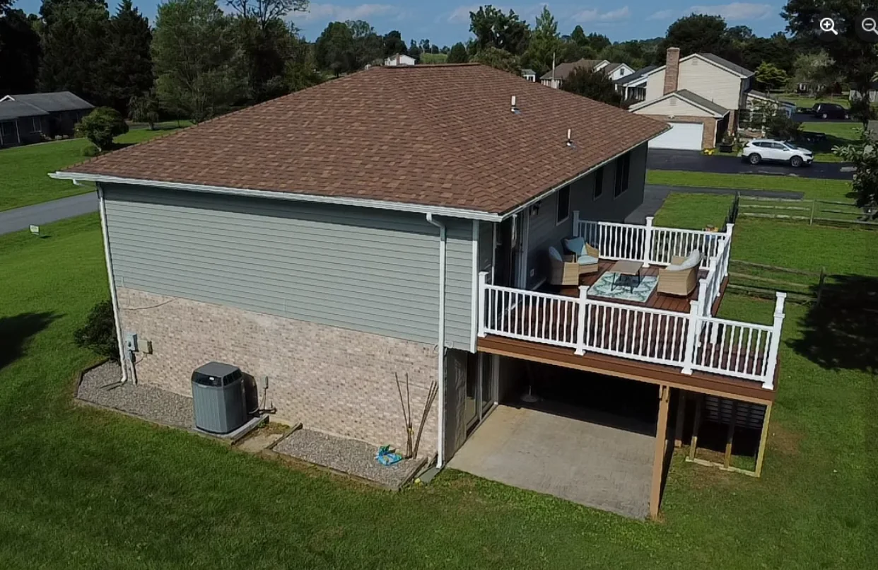 Aerial view of a home with a roof and elevated deck